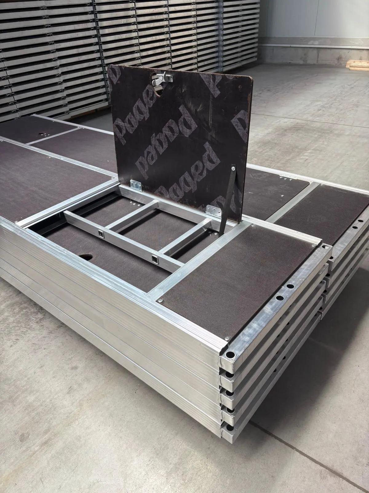 Plancher d'échafaudage en aluminium équipé d'une trappe d'accès et d'une échelle intégrée, posé en entrepôt